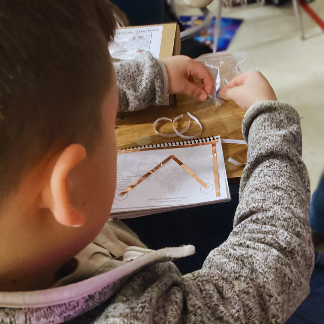 Kids building circuits with glowing Harley-Davidson models from a science kit.